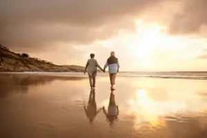 Active couple walking outdoors at sunrise representing healthy aging and restoring the body's natural balance.